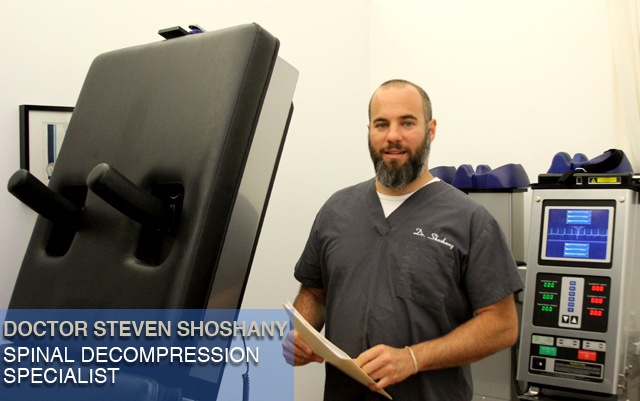 Our spinal decompression NYC expert Dr Shoshany stands in front of the DRX 9000, a computerized table for spinal decompression therapyNYC